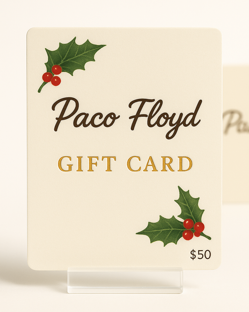 Paco Floyd Holiday Gift Card displayed in a clear acrylic stand on a soft neutral background, featuring gold-embossed lettering and festive holly illustrations in the corners — elegant holiday gift option for pet portrait lovers.