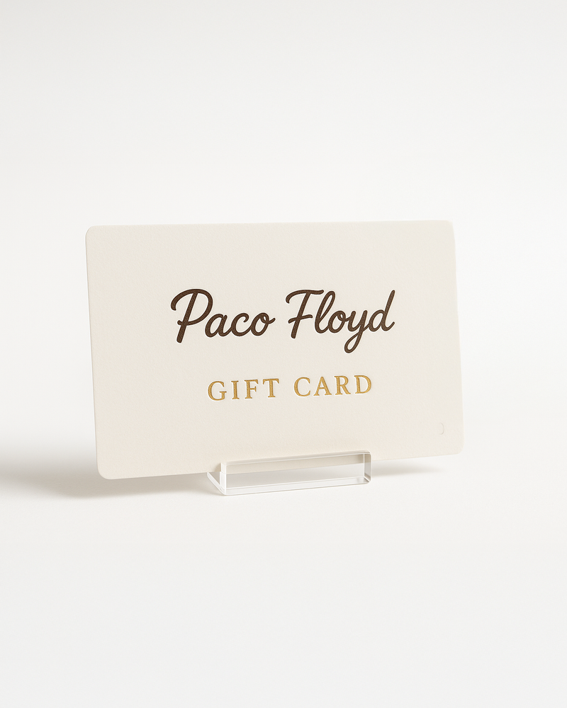 Paco Floyd Holiday Gift Card displayed in a clear acrylic stand on a soft neutral background, featuring gold-embossed lettering and festive holly illustrations in the corners — elegant holiday gift option for pet portrait lovers.